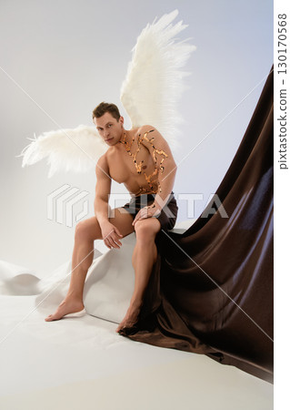 Model with angel wings and artistic body adornments poses against backdrop Model with angel wings and artistic body adornments poses against backdrop 130170568