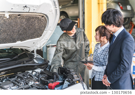 一名機械師在汽車引擎室內進行解說，修理廠的工作人員正在聽他講解 130170656