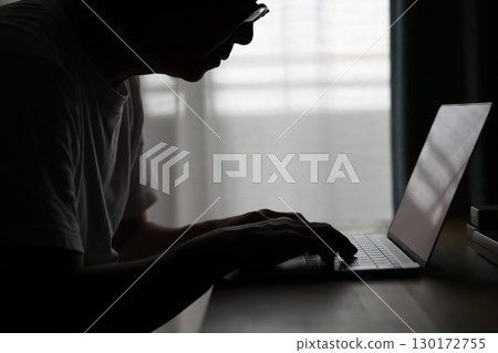 一個人在黑暗的房間裡使用電腦 130172755