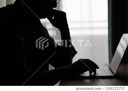 一個人在黑暗的房間裡使用電腦 130172757