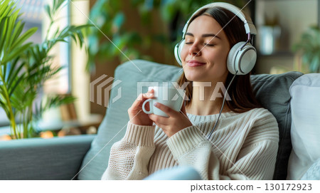 a relax woman hold white cup of coffee for mock up to wearing headphone. 130172923