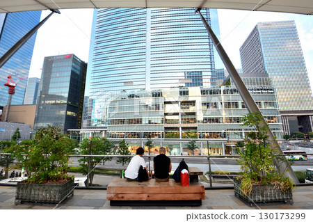 Three people resting on the Gran Roof bench at the Yaesu exit of Tokyo Station 130173299