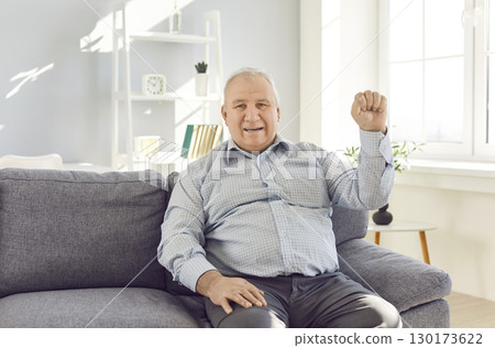 Portrait of optimistic handsome senior confident happy mature man sitting on sofa looking at camera Portrait of optimistic handsome senior confident happy mature man sitting on sofa looking at camera 130173622
