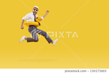 Funny young man in rubber ring is going on jumping going on summer holiday on yellow background. 130173803