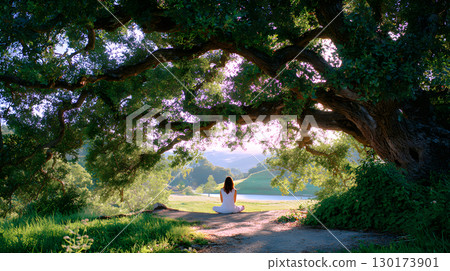 A peaceful moment of a person sitting quietly under a large tree with no devices, embracing nature. Ideal for wellness, mindfulness, and slow living themes. 130173901