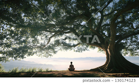 A peaceful moment of a person sitting quietly under a large tree with no devices, embracing nature. Ideal for wellness, mindfulness, and slow living themes. 130174123
