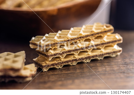 Sweet crispy wafers on wooden table. 130174407