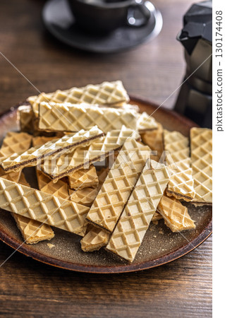 Sweet crispy wafers on plate on wooden table. Sweet crispy wafers on plate on wooden table. 130174408