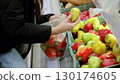 Customer choosing vibrant bell peppers from a grocery store display and packing a plastic bag with fresh produce for a nutritious diet 130174605