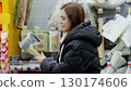 Customer inspecting a freshly packaged axe at a hardware store, contemplating a potential buy for home improvement or outdoor use 130174606
