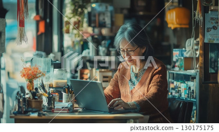 Senior Woman Working on Laptop in Cozy Cafe 130175175