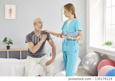 An elderly man complains of shoulder pain to a woman doctor An elderly man complains of shoulder pain to a woman doctor 130176128