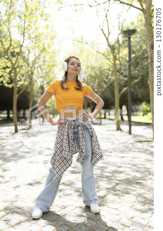 Young stylish woman listening to music on wireless headphones in park Young stylish woman listening to music on wireless headphones in park 130176705