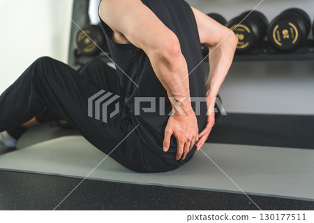 A man in sportswear suffering from back pain during training 130177511