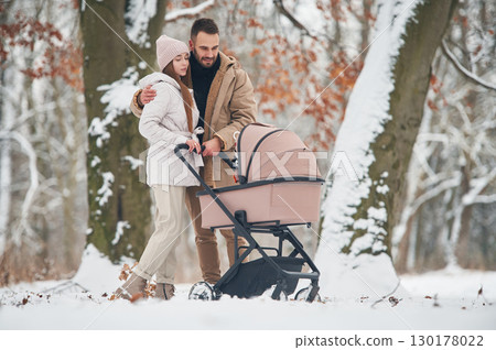 Mother and father with pram. Lovely couple have a walk in the winter forest Mother and father with pram. Lovely couple have a walk in the winter forest 130178022