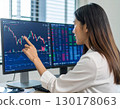 A young business person, trader, female investor, looking at stock price trends and pointing 130178063