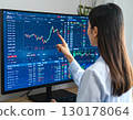 A young business person, trader, female investor, looking at stock price trends and pointing 130178064