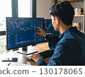 A young business person, trader, male investor, looking at stock price trends and pointing 130178065