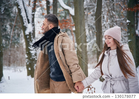 Holding hands. Lovely couple have a walk in the winter forest 130178077