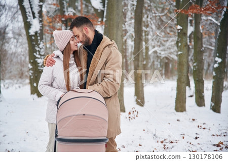 Parents with pram. Lovely couple have a walk in the winter forest Parents with pram. Lovely couple have a walk in the winter forest 130178106