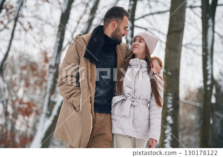 Looking at each other. Lovely couple have a walk in the winter forest Looking at each other. Lovely couple have a walk in the winter forest 130178122
