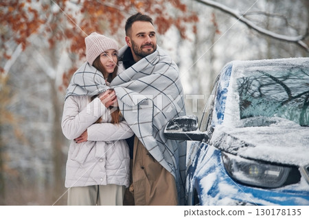 Warming by towel. Happy couple having a walk in winter forest. Blue car is parked Warming by towel. Happy couple having a walk in winter forest. Blue car is parked 130178135