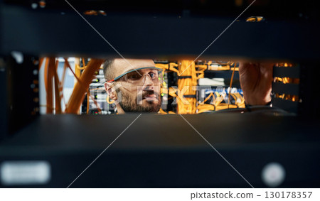 Young man is working with internet equipment and wires in server room Young man is working with internet equipment and wires in server room 130178357