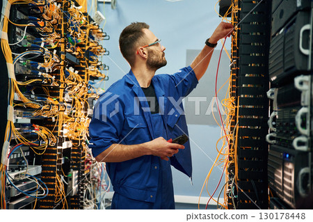 Cutting the wire. Young man is working with internet equipment in server room 130178448