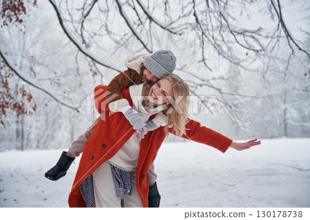 Holding girl by hands on spine. Mother and her daughter is on the winter meadow and forest Holding girl by hands on spine. Mother and her daughter is on the winter meadow and forest 130178738