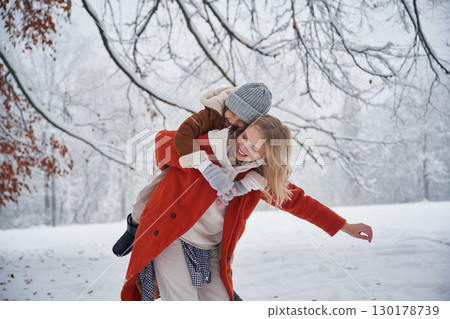 Holding girl by hands on spine. Mother and her daughter is on the winter meadow and forest Holding girl by hands on spine. Mother and her daughter is on the winter meadow and forest 130178739