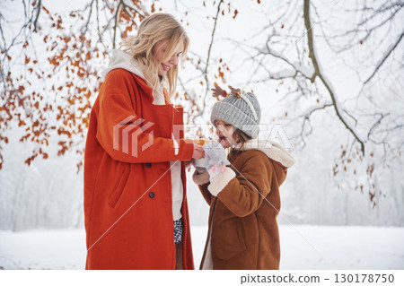 With sweet food. Mother and her daughter is on the winter meadow and forest With sweet food. Mother and her daughter is on the winter meadow and forest 130178750