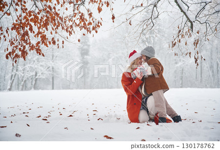 In Santa clothes, with gift box. Mother and her daughter is on the winter meadow and forest In Santa clothes, with gift box. Mother and her daughter is on the winter meadow and forest 130178762