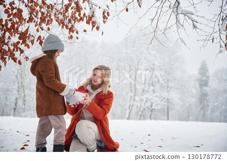 New year present in gift box. Mother and her daughter is on the winter meadow and forest 130178772