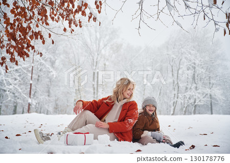 New year present in gift box. Mother and her daughter is on the winter meadow and forest 130178776