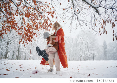 Playing and having fun. Mother and her daughter is on the winter meadow and forest 130178784