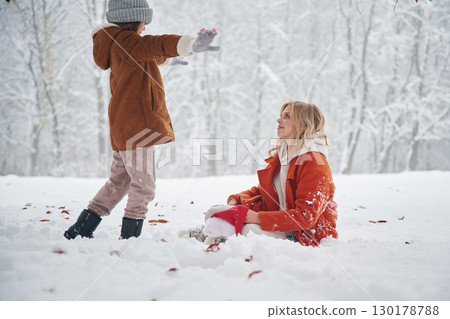 Playing and having fun. Mother and her daughter is on the winter meadow and forest 130178788