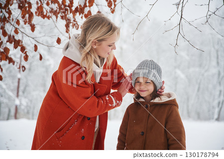 Wearing the hat to the girl. Mother and her daughter is on the winter meadow and forest 130178794