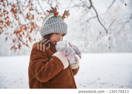 With cup of drink. Portrait of cute little girl on the winter field 130178813