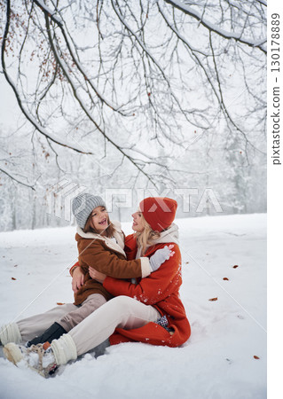Sitting on the ground. Mother and her daughter is on the winter meadow and forest Sitting on the ground. Mother and her daughter is on the winter meadow and forest 130178889