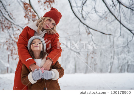 Standing and posing. Mother and her daughter is on the winter meadow and forest 130178900