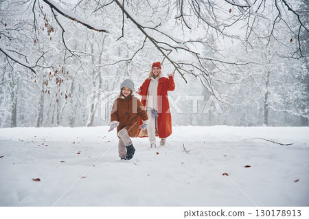 Running forward. Mother and her daughter is on the winter meadow and forest Running forward. Mother and her daughter is on the winter meadow and forest 130178913