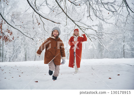 Running forward. Mother and her daughter is on the winter meadow and forest Running forward. Mother and her daughter is on the winter meadow and forest 130178915