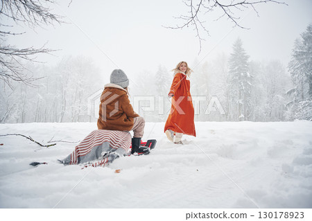 Sled ride. Mother and her daughter is on the winter meadow and forest Sled ride. Mother and her daughter is on the winter meadow and forest 130178923