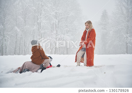 Sled ride. Mother and her daughter is on the winter meadow and forest 130178926