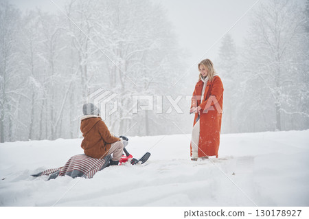 Sled ride. Mother and her daughter is on the winter meadow and forest Sled ride. Mother and her daughter is on the winter meadow and forest 130178927