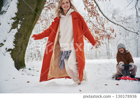 Having fun by sled ride. Mother and her daughter is on the winter meadow and forest Having fun by sled ride. Mother and her daughter is on the winter meadow and forest 130178936