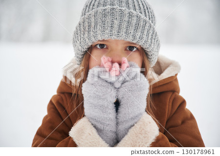 Shocked, covering face with hands. Portrait of cute little girl on the winter field 130178961