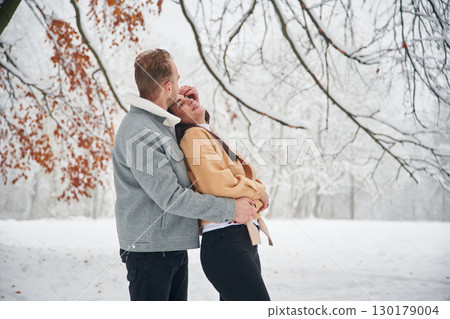 Standing and enjoying snow. Beautiful couple are together on the field of forest 130179004