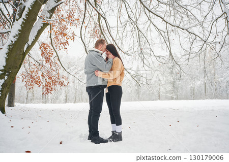 Beautiful couple are standing together on the snowy field of forest 130179006