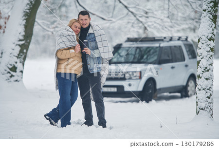 Embracing each other. Beautiful couple standing near the car in the winter forest Embracing each other. Beautiful couple standing near the car in the winter forest 130179286